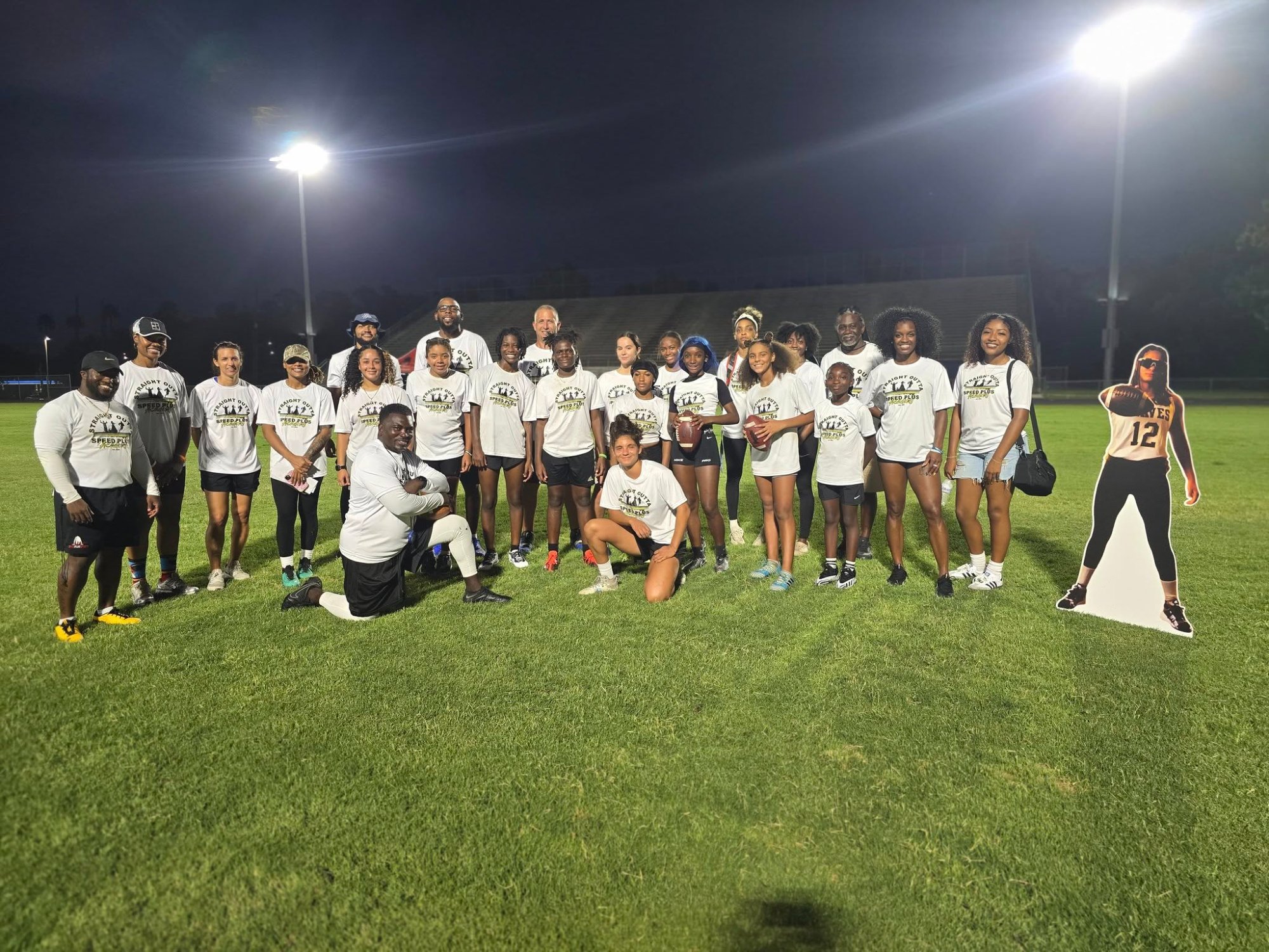 Speed Plus Academy female athletes in white shirts on lit field at night