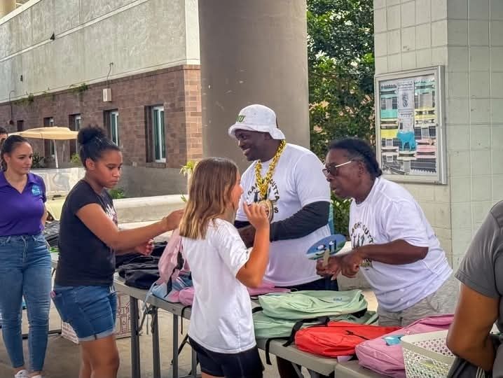 Coach BoJack and volunteers handing out backpacks at Back to School supply drive