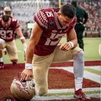 Speed Plus Academy alumni kneeling in prayer in football end zone